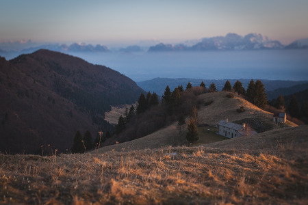 Sunrise on a small hut with in the background the Dolomiti Bellunesi  peaks tilt shift effect, Pian...