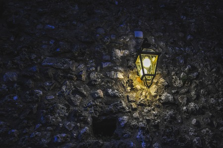 Isolated lamppost lit on a stone wallの写真素材