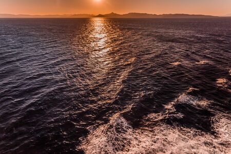 Awesome sunset reflections over the sea with islands of Saronic Gulf backgroundの写真素材