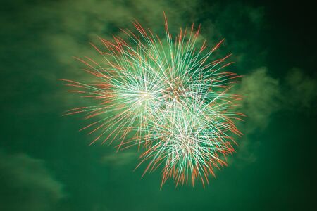 Bright red, white and green fireworks against the backdrop of the night skyの写真素材