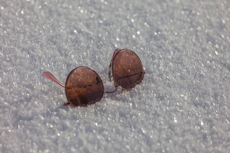 Sunglasses over a snowy surface with brilliant crystals, Dolomites, Italy