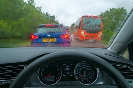 Dashboard and wet car glass with another blurred car and bus in the background. Concept: drive on...