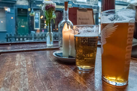 Beer glasses on a table near a candle