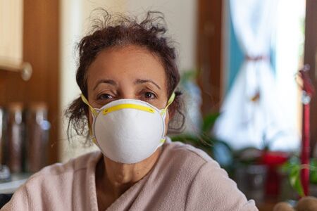 Woman with tousled hair and mask closed at home for coronavirus quarantineの写真素材