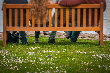 Detail of legs of unrecognizable people sitting on a bench, Scotlandの写真素材