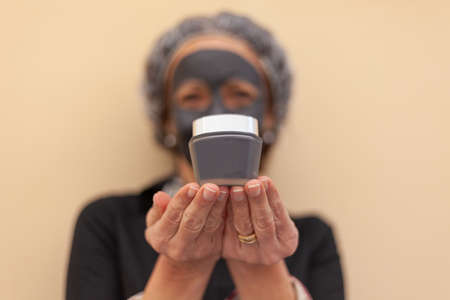 Close up of hands holding a jar of face cream. Blurry woman on the background. Image relating to the care and beauty of the female bodyの写真素材