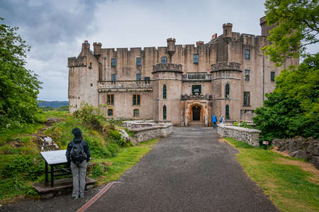 Sporty dressed girl looking at the entrance to Dunvegan Castle, Scotland. Concept: visiting places with charm and mystery, travel to Scotlandのeditorial素材