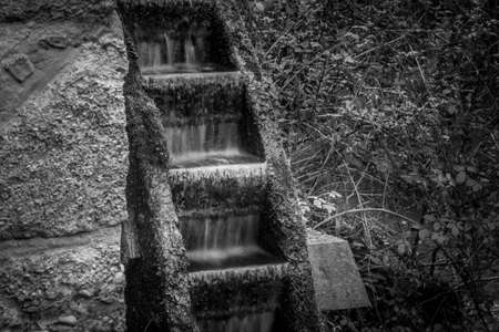 Black and white effect of the water flowing into an ancient mill wheel