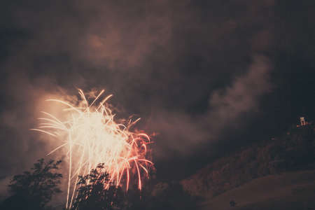 Awesome white and red fireworks fountains above trees with vintage color effectの写真素材