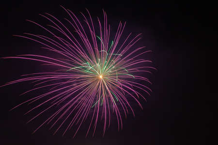 Bright purple and green fireworks against the backdrop of the night skyの写真素材