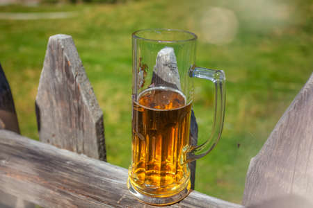 Glass of beer leaning against a wooden fenceの写真素材
