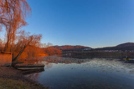 Reflections of hills on a lake with boats during an autumn sunsetの写真素材