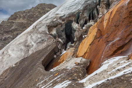 Holes in the ice at the base of the Vallelunga glacier above red rocksの写真素材