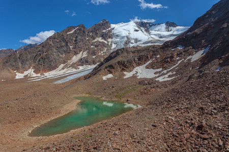 Turquoise glacial lake among ancient moraines at the foots of majestic glacierの写真素材