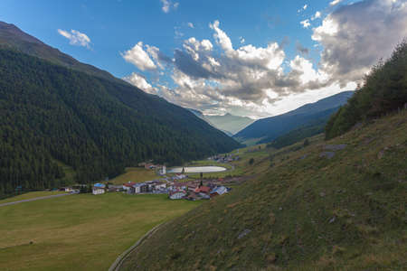 Sunset panorama of alpine valley with small village and lakeの写真素材