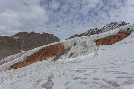 Vallelunga glacier flowing over red mountain rocks, Alto Adige, Italyの写真素材
