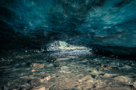 Awesome blue ice cave carved into the Vallelunga glacier crossed by a streamの写真素材