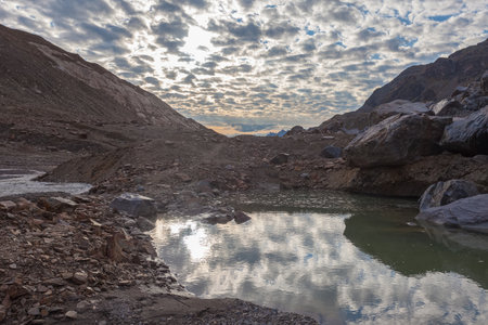 Small lake and stream generated by Vallelunga glacier melting at sunsetの写真素材