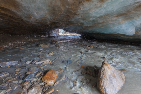 Entrance of ice cave carved into the Vallelunga glacier crossed by a streamの写真素材
