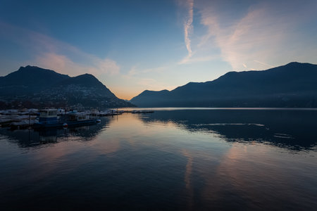 Panorama of Lugano lake in autumn early morning with mooring for pleasure boatsの写真素材