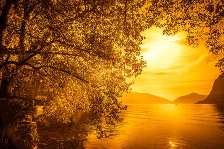 Fantasy orange color image effect on the shore of Lugano lake, Switzerlandの写真素材
