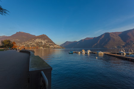 Sunset autumnal view of the Lugano lake with mooring for pleasure boats.のeditorial素材