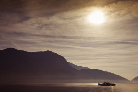 Boat sailing on Lake Lugano during a dramatic sunriseの写真素材