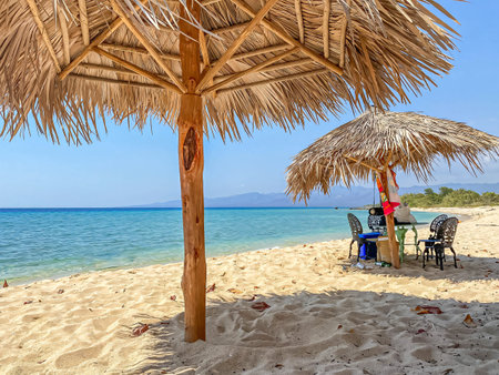 Relaxing on a cuban beach with straw umbrellas and turquoise waterの写真素材