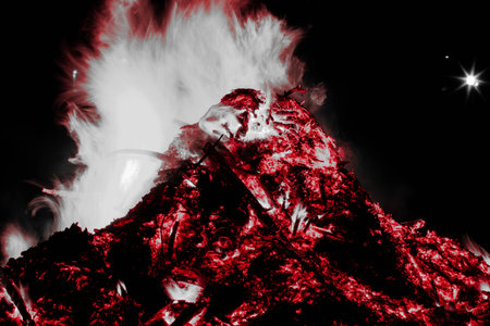 Burning red bonfire with glowing embers at night