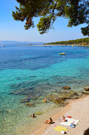Island of Brac, Croatia, 08/28/2017. People on vacation on a beach in Bol, a village on an island in the Adriatic Sea.のeditorial素材