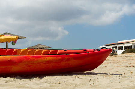 A red canoe on the sand during a sunny day.の写真素材