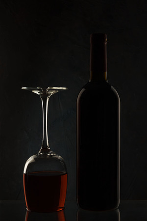 Bottle and glass with wine on a dark  in backlitの写真素材