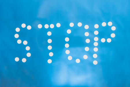 Variety of pills and drugs forming the word STOP in english text as a message against human...