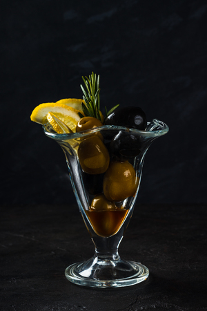 Snack of green and black olives, lemon with a sprig of rosemaryの写真素材