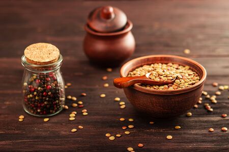 Lentils in a clay vessel on and wooden spoon on a wooden