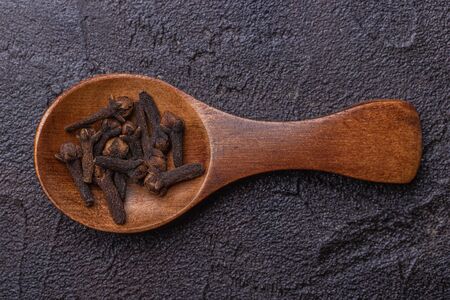 Wooden spoon with cloves on a dark concrete backgroundの写真素材
