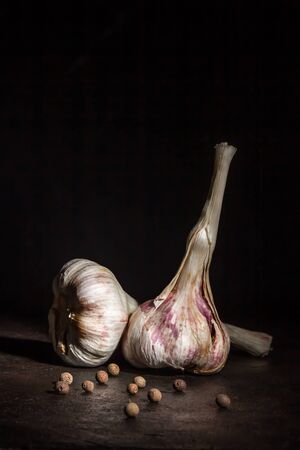 Two heads of garlic and black pepper on darkの写真素材