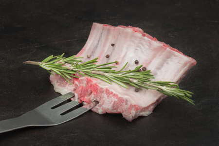 Raw pork ribs with rosemary on a barbecue forkの写真素材