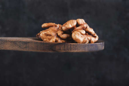 Walnut in a wooden spoon on a dark background