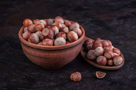 Hazelnuts in a clay cup and a wooden spoon