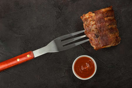 Baked pork strung on a barbecue fork with red sauceの写真素材