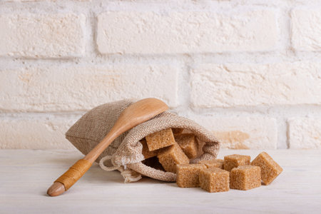 Cubes of cane sugar in a bag with a wooden spoonの写真素材