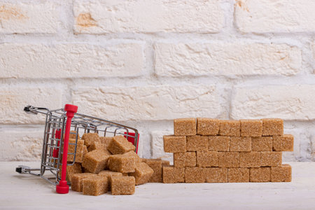 Inverted trolley with brown cane sugar and a wall of their sugar cubesの写真素材
