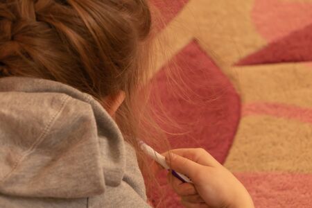 A little girl brushes her teeth, photographed from behind
