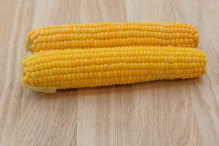 Boiled corn on a wooden background. Ready to eat. Corn benefits.の写真素材