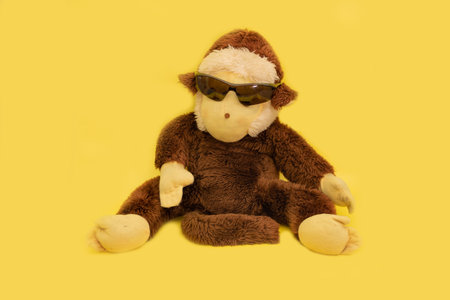 Plush monkey with sunglasses dressed on a yellow backgroundの写真素材