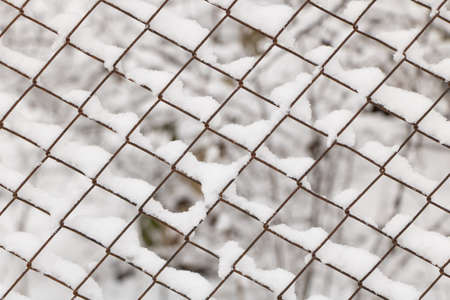 Metal mesh is covered with snow - snow texture - winter scene concept.