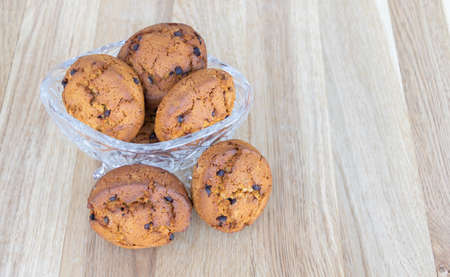Cookies with brown chocolate in a crystal cup with wood background.