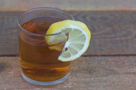 Black tea in a glass with a slice of lemon - Concept of benefits of tea with lemon juice on wooden backgroud.の写真素材