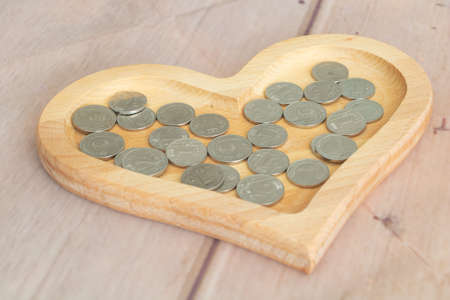 Metal coins in Moldovan lei currency 1 leu - 2lei in a heart-shaped wooden plateの写真素材